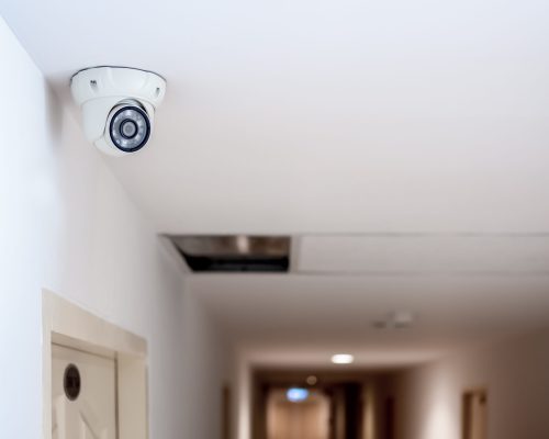 Security camera White security CCTV Camera or surveillance operating on ceiling in front of the door room in condominium with copy space.